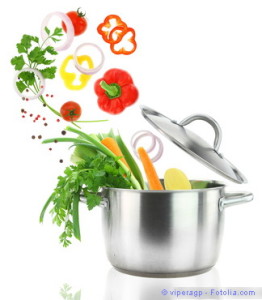 Fresh vegetables falling into a stainless steel casserole pot